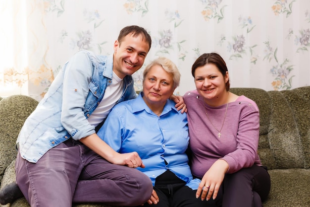 Des petits-enfants adultes souriants embrassent une grand-mère âgée heureuse de voir qu'elle lui manque, la visite de parents aimants apprécie la communication, les câlins comme symbole de connexion, d'amour et de concept de soutien