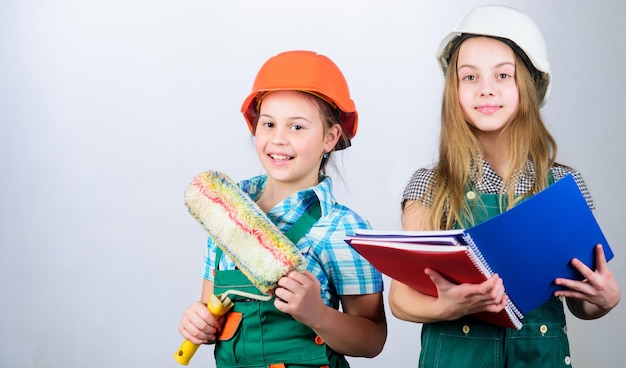 Petits enfants en casque avec tablette et rouleau Fête du travail 1 mai petites filles réparant ensemble dans l'atelier Inspecteur contremaître Projet d'école de réparation équipe réussie entreprise réussie