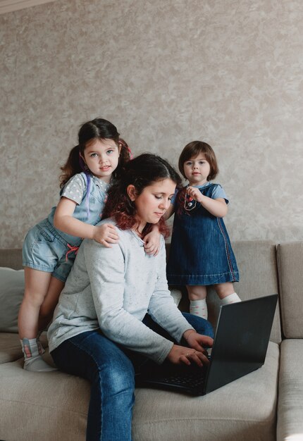 Les petits enfants empêchent leur mère de travailler sur l'ordinateur. travail à distance à domicile