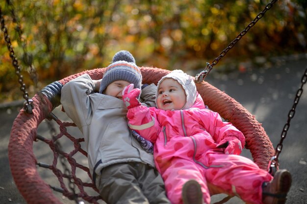 Les petits enfants garçon et fille montent sur une balançoire