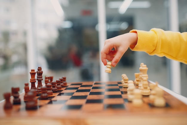 Petits enfants jouant aux échecs à la maternelle ou à l'école primaire. La main tient la figure d'échecs en gros plan.