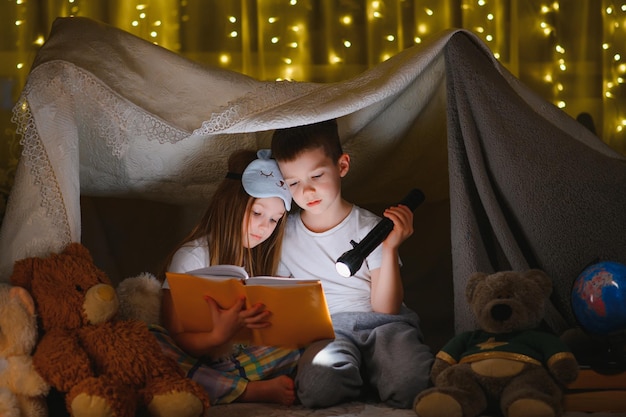 Petits enfants lisant une histoire au coucher à la maison