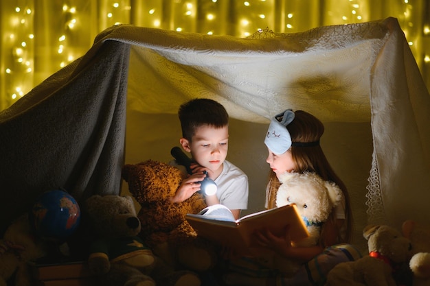 Petits enfants lisant une histoire au coucher à la maison