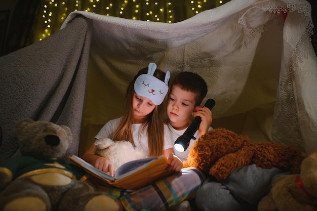 Petits enfants lisant une histoire au coucher à la maison