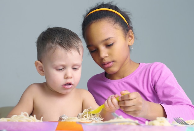 Petits enfants mangeant des spaghettis. nourriture traditionnelle des enfants