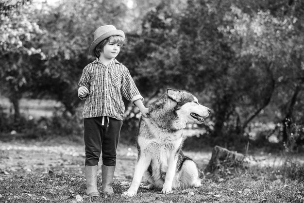 Petits enfants marchant avec leur chien de compagnie à l'extérieur les enfants s'amusant chien animal de compagnie dans le champ contre na