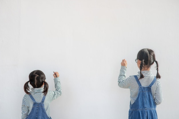 Petits enfants peignant sur un mur blanc