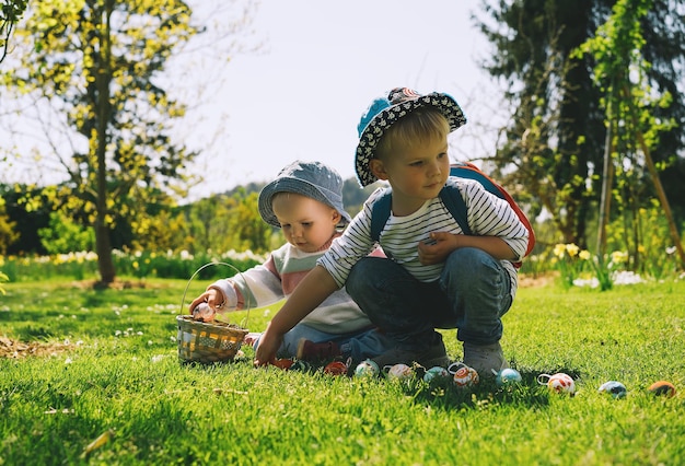 Petits enfants rassemblant des œufs de décoration peints dans le parc du printemps Les enfants chassent les œufs à l'extérieur Jeu de jeu traditionnel familial festif à Pâques