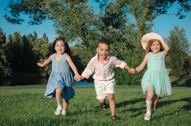 Les petits enfants s'amusent sur la pelouse. deux filles et un garçon