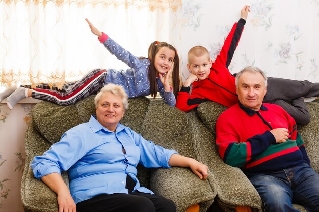 Petits-enfants sautant sur le canapé avec leurs grands-parents dans le salon