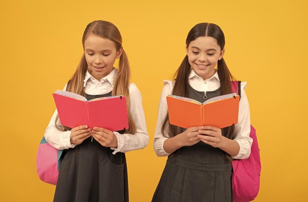 Les petits enfants en uniforme scolaire lisent des livres de bibliothèque lecture de fond jaune