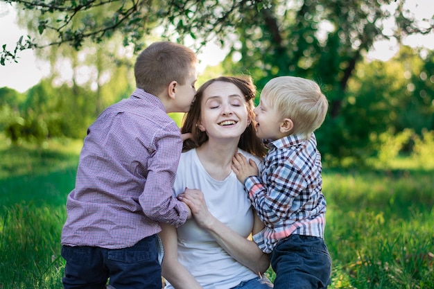 Petits fils embrassent maman sur la joue Heureuse mère avec deux enfants dans la nature