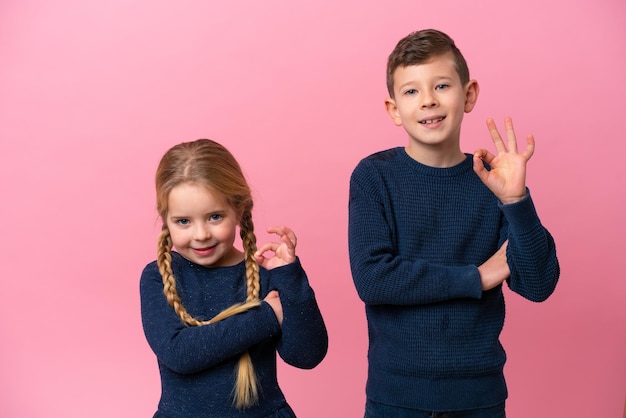 Petits frères caucasiens isolés sur fond rose montrant un signe ok avec les doigts