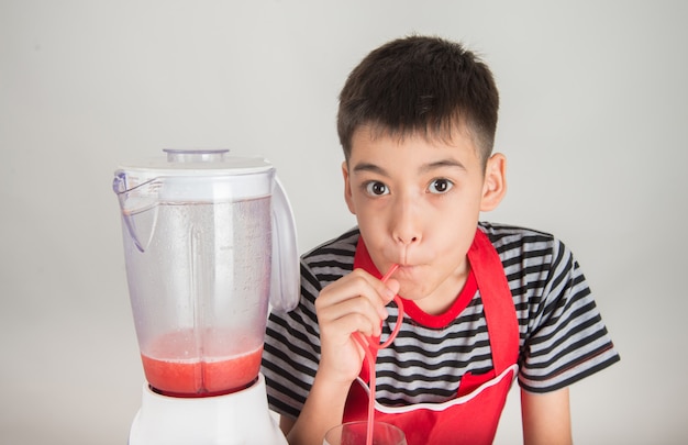 Petits garçons mélangent le jus de melone d&#39;eau en utilisant un mélangeur à la maison