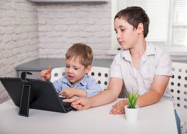 Les petits garçons qui suivent des cours en ligne dans le salon restent à la maison