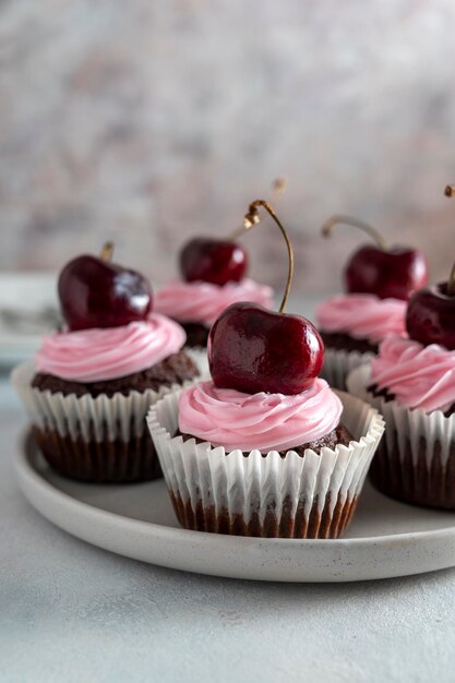 Petits gâteaux au chocolat aux cerises avec crème rose Pâtisserie ou dessert fait maison