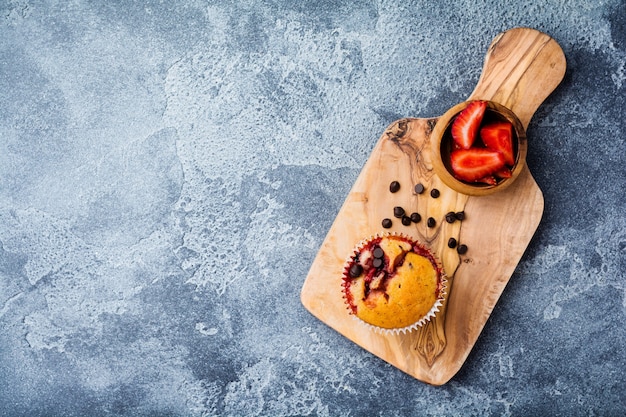 Petits gâteaux au chocolat aux fraises muffins sur vieux support en bois sur une surface gris béton