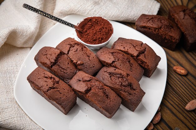 Petits gâteaux au chocolat avec du cacao à la menthe et des fèves de cacao sur une table en bois