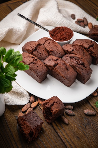 Petits gâteaux au chocolat avec du cacao à la menthe et des fèves de cacao sur une table en bois