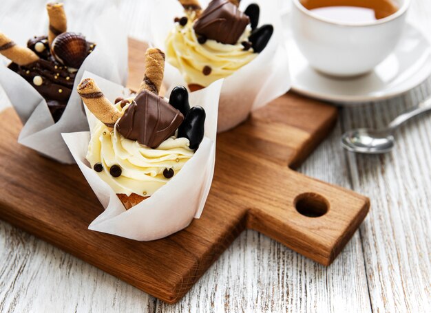 Petits gâteaux au chocolat et tasse de thé sur une table en bois blanc