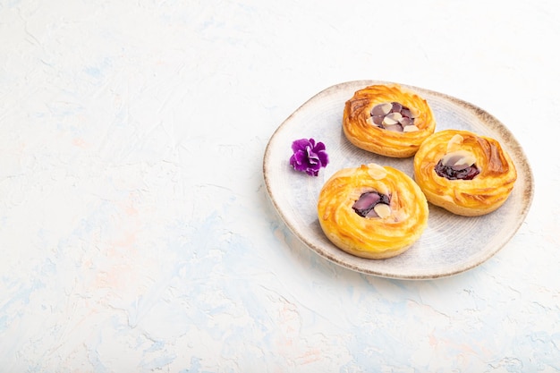 Petits gâteaux au fromage avec confiture et amandes avec tasse de café sur fond de béton blanc. Vue latérale, espace de copie, gros plan.