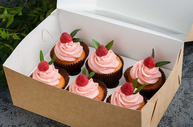 Petits gâteaux à la crème de framboise, décorés avec des framboises sur l&#39;emballage cadeau.