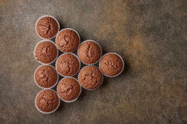 Petits gâteaux faits maison au chocolat disposés sous forme de triangle sur une surface en bois, espace copie, haut