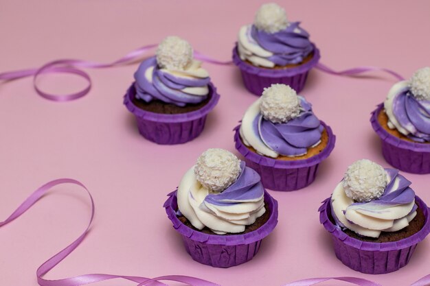 Petits gâteaux faits maison avec de la crème lilas sur fond rose, concept pour la Saint Valentin ou anniversaire, orientation horizontale