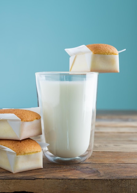 Petits gâteaux faits maison avec un verre de lait sur une table en bois avec un fond bleu. Espace de copie. photo verticale. Madeleines faites à la main.