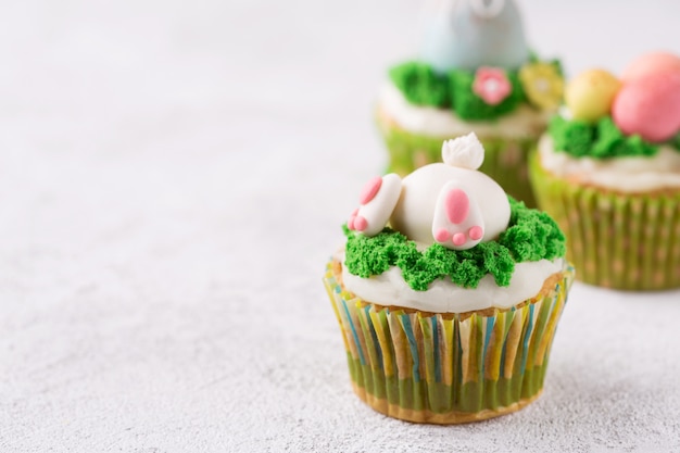 Photo petits gâteaux de pâques avec lapin drôle et herbe sur fond blanc. concept de vacances de pâques