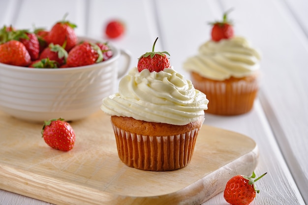 Petits gâteaux savoureux avec des fraises et une crème douce sur fond blanc