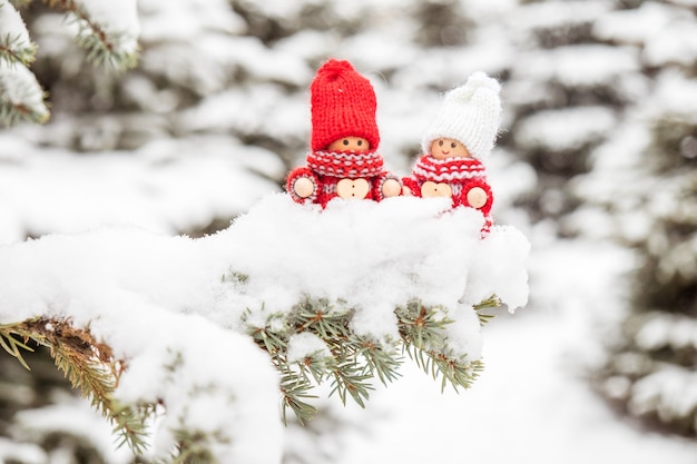 Petits jouets mignons de Noël sur une branche de sapin couverte de neige