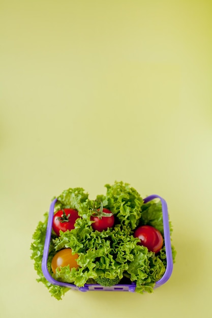 Petits légumes frais dans le panier sur fond jaune Concept de fond alimentaire avec fond