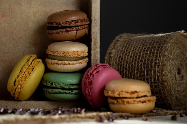 petits macarons multicolores dans une boîte en bois sur fond sombre