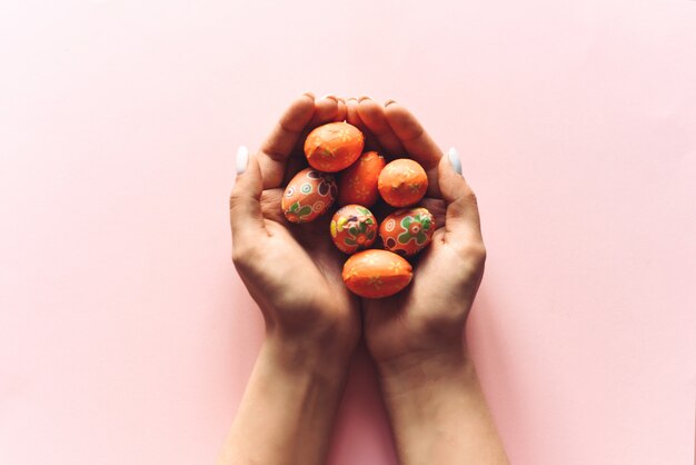 Petits oeufs décoratifs de Pâques dans les mains d'une fille sur fond rose. Belle illustration de Pâques