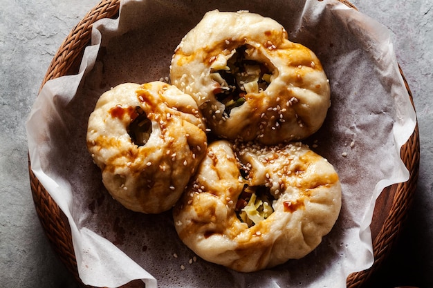 Petits pains Baozi aux légumes et champignons dans un panier en bois sur une table en béton