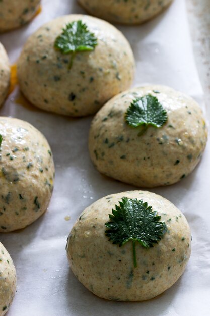 Petits pains à base de pâte de levure aux orties, décorés de feuilles d'ortie sur une poêle en fer.