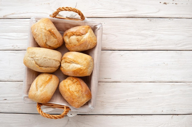 Photo petits pains de blé frais dans un panier en osier sur une table en bois blanc