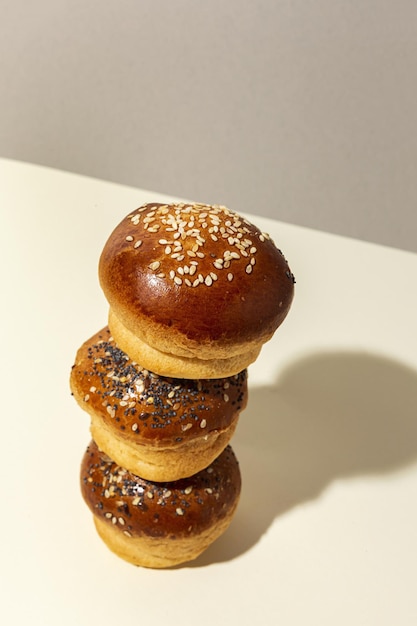 Petits pains briochés faits maison ronds assortis avec des graines sur un fond coloré avec une lumière à contraste élevé