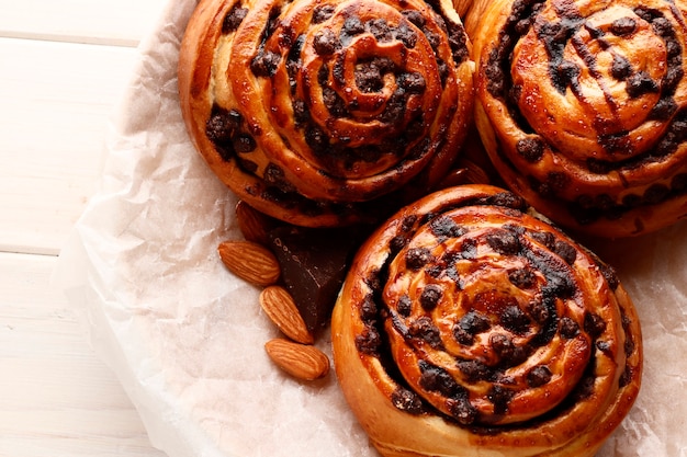 Petits pains à la cannelle et au chocolat sur un fond en bois marron. Bâton de cannelle et café expresso noir. Place pour le texte. Vue de dessus.