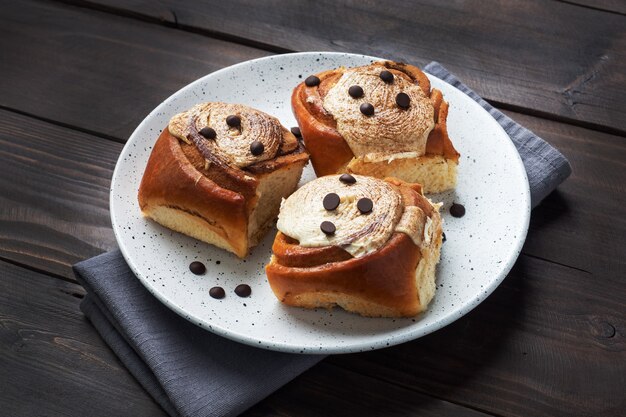 Petits pains à la cannelle Kanelbulle avec crème au beurre sur une table en bois rustique. Pâtisseries fraîches faites maison.