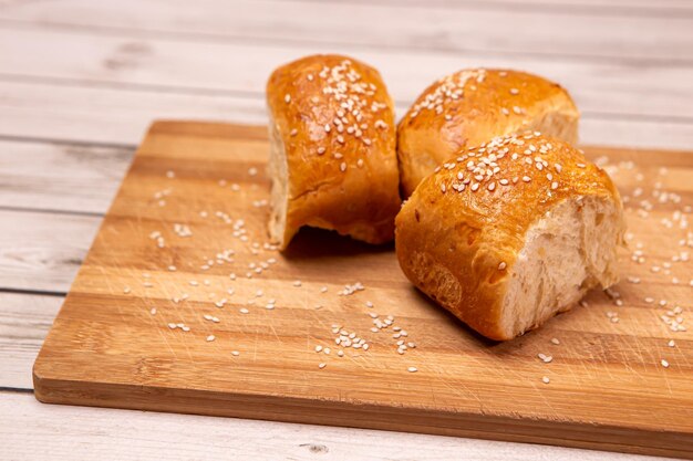 Petits pains chauds frais avec des graines sur un bureau en bois