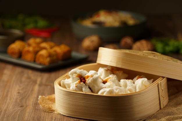 Petits pains chinois cuits à la vapeur avec du porc haché rouge sur une assiette et des paniers en bambou. Cuisine asiatique cuisine traditionnelle chinoise.