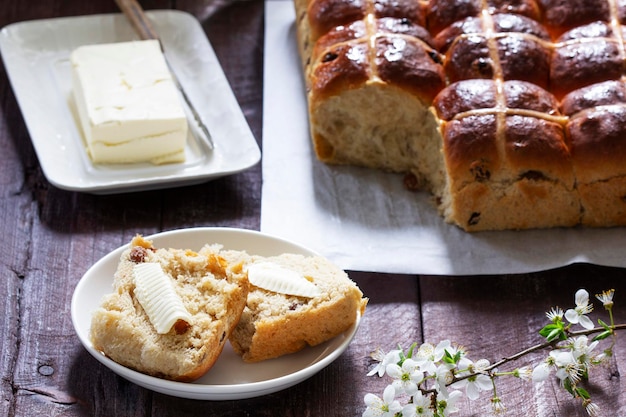 Petits pains croisés servis avec beurre, miel et thé petit-déjeuner de pâques