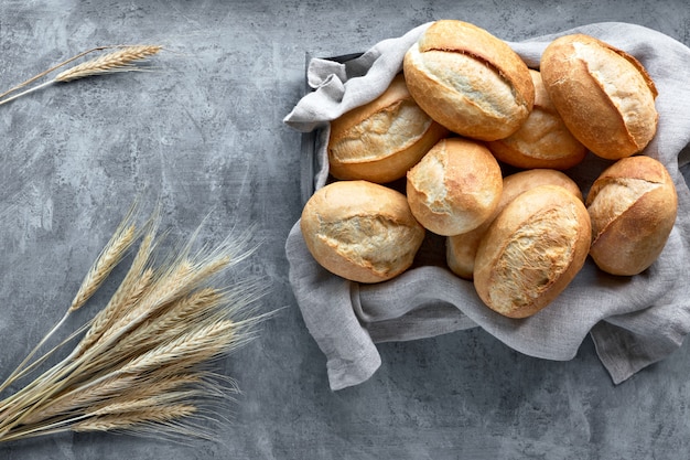 Petits pains dans un panier en bois rustique avec des épis de blé