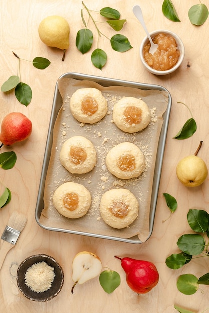 Petits pains faits maison crus à base de pâte à levure avec de la confiture et des poires fraîches Mini tartes Recette de cuisine sur fond de bois