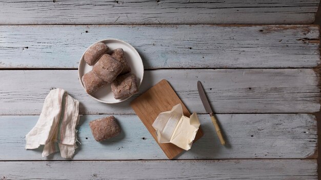 Petits pains de farine au son avec du beurre sur une table en bois, vue de dessus