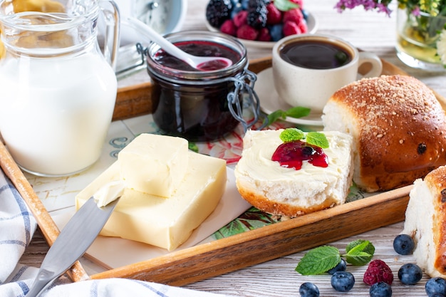 Petits pains frais faits maison servis avec du beurre et de la confiture. Déjeuner