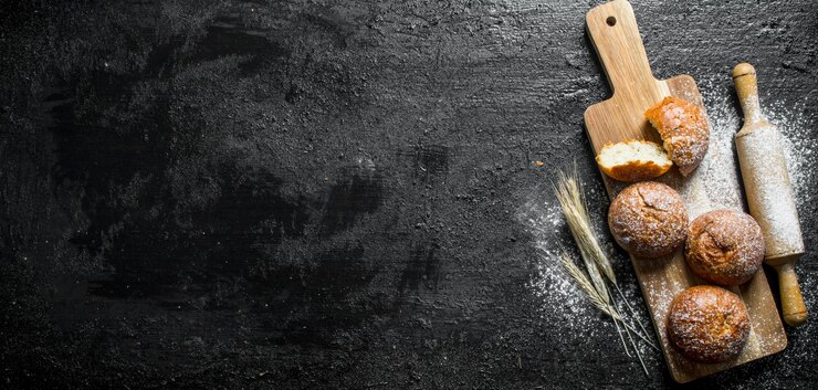 Photo petits pains frais sur une planche à découper en bois avec un rouleau à pâtisserie et des épillets