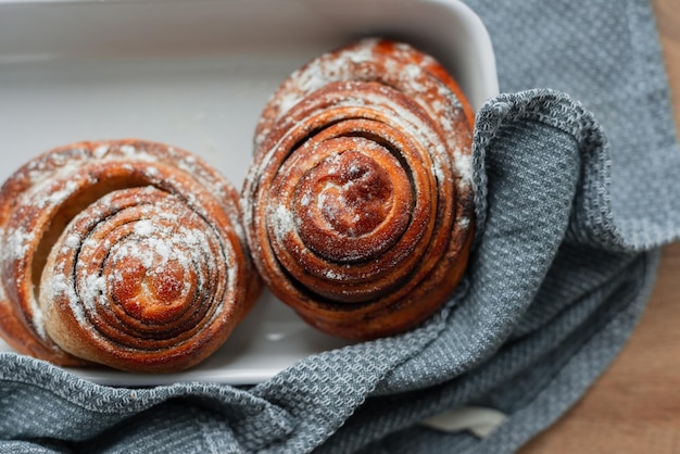 Des petits pains frais se trouvent sur un plateau en céramique avec des essuie-tout vue de dessus Boulangerie de produits à base de farine sucrée